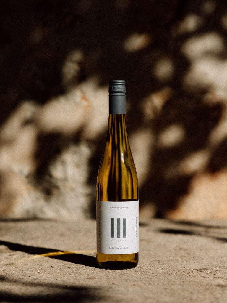 Drei Freunde Grauburgunder Weisswein Trocken Flasche auf Beton mit unscharfem Hintergrund