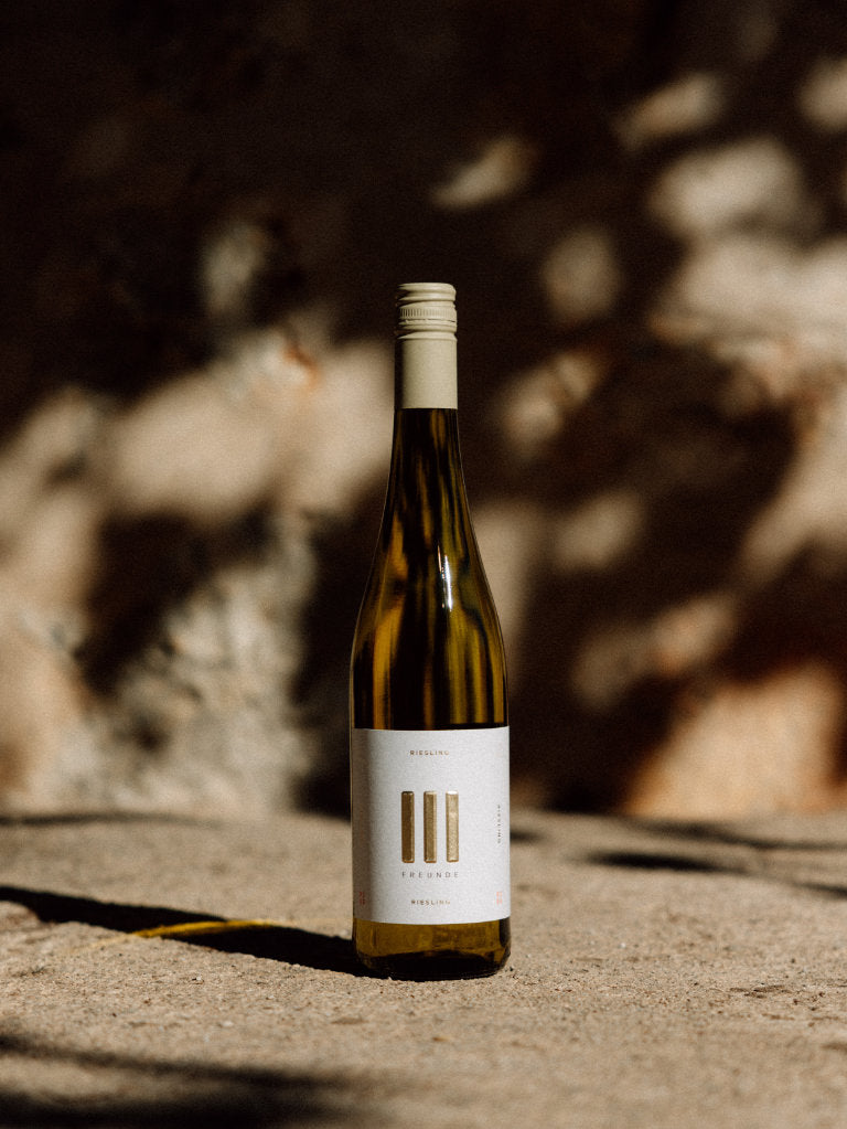 III Freunde Riesling Flasche vor Mauer