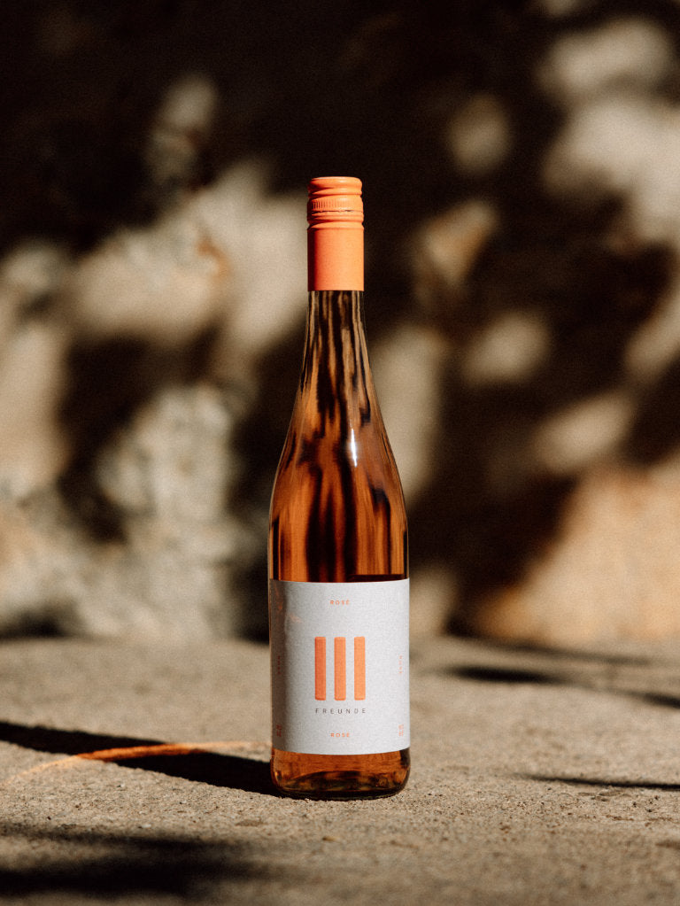 III Freunde Rosé Weinflasche vor einer Mauer