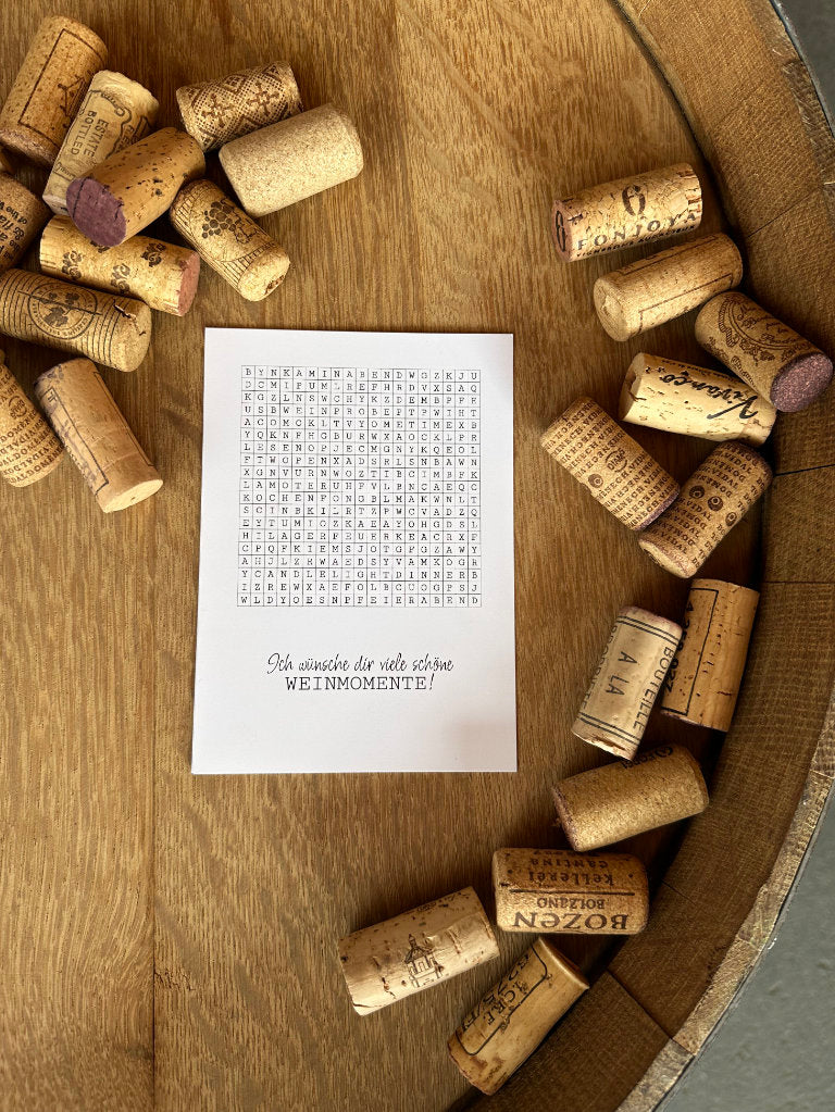 Grußkarte Rätsel voller Weinmomente fotografiert auf Fass mit Korken