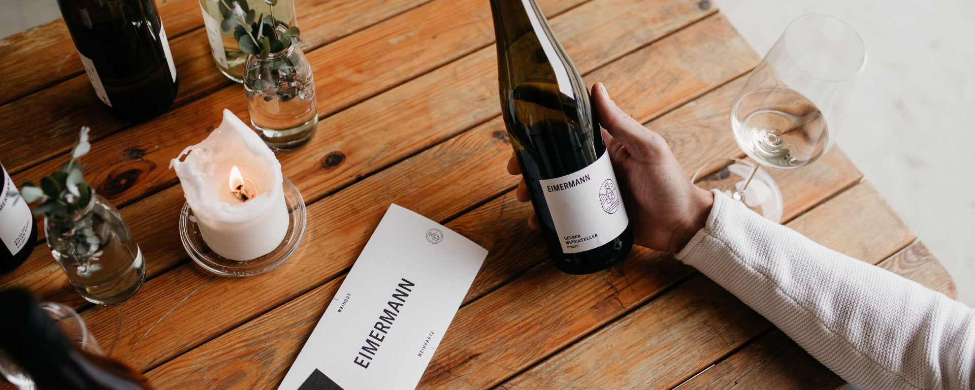 Weingut Eimermann Blick auf Tisch mit Kerzen und einer Flasche Gelbem Muskateller