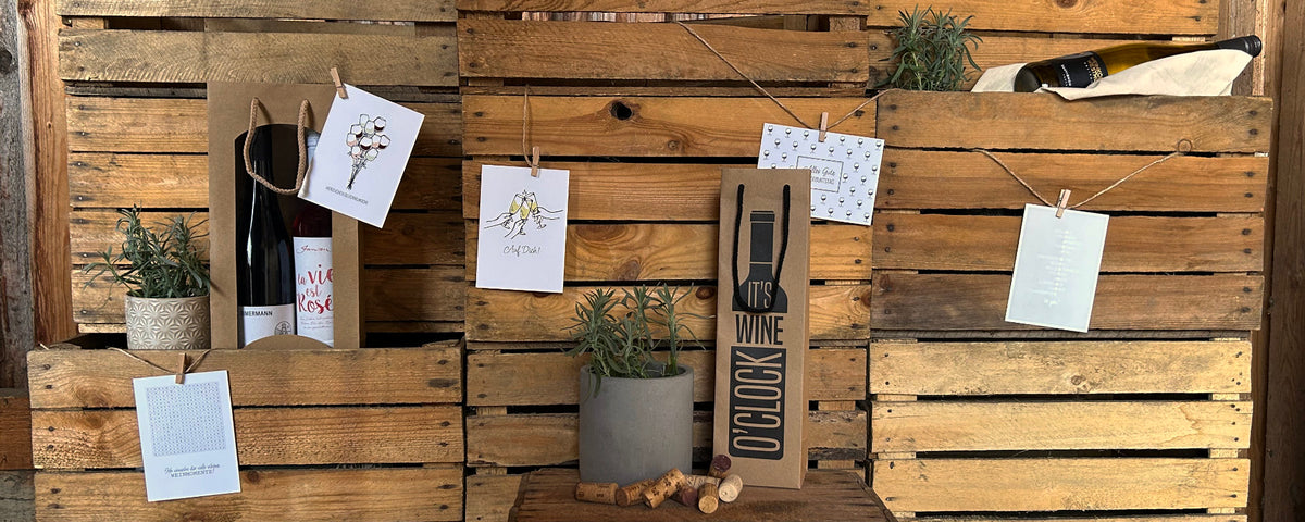 Imagebild für Wein Verschenken verschiedene Grußkarten für Wein und Geschenkverpackungen vor stilvollem Holzhintergrund