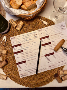 Verkostungsheft für Wein aufgeschlagen auf Tisch mit Deko