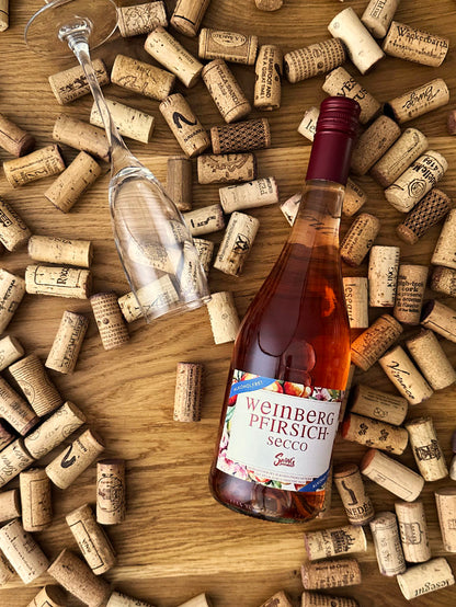 Weinbergpfirsich Secco Roséwein auf Holz im Korkbett